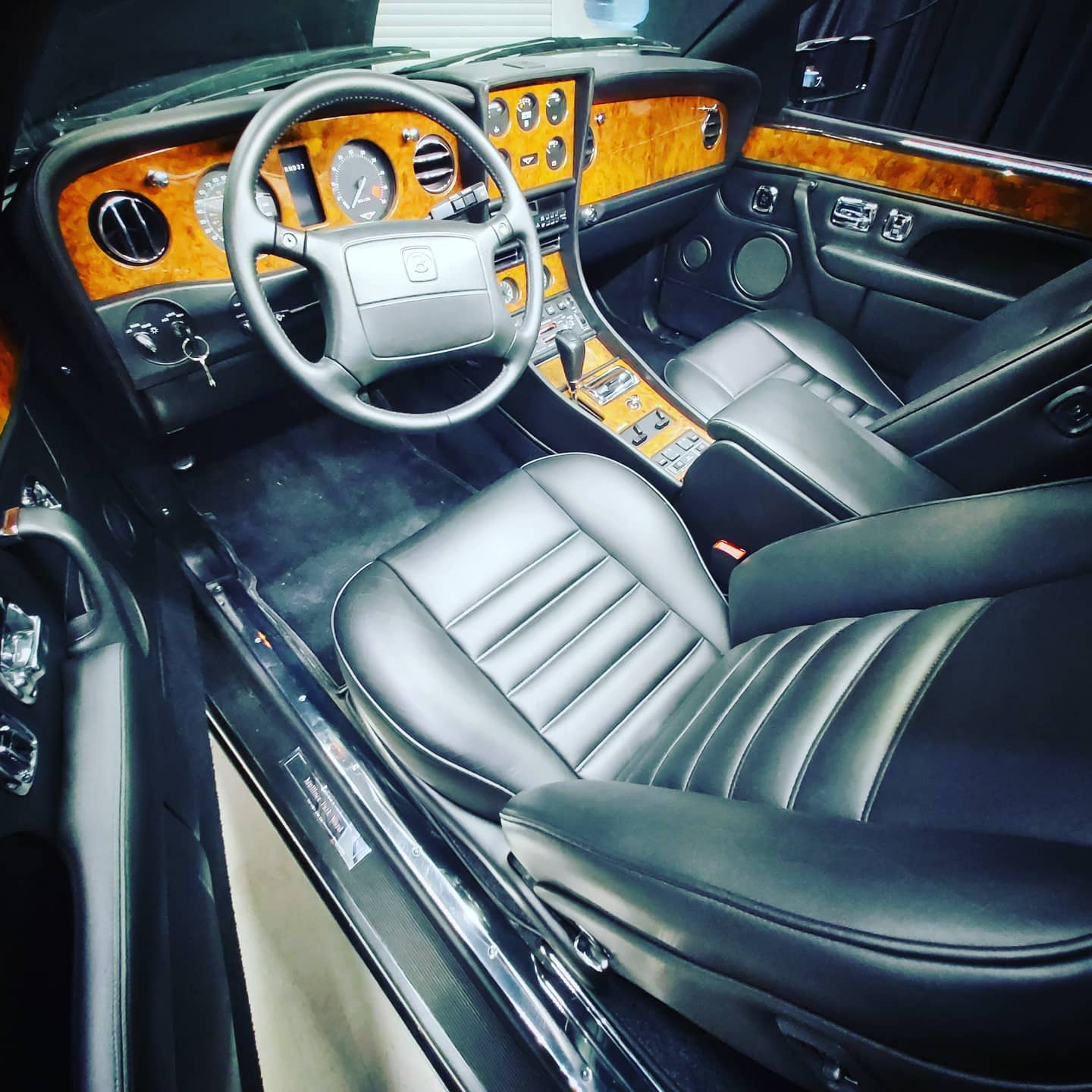 Wnętrze eleganckiego samochodu z kierownicą po lewej stronie, podkreślające wyjątkowy charakter pojazdu.